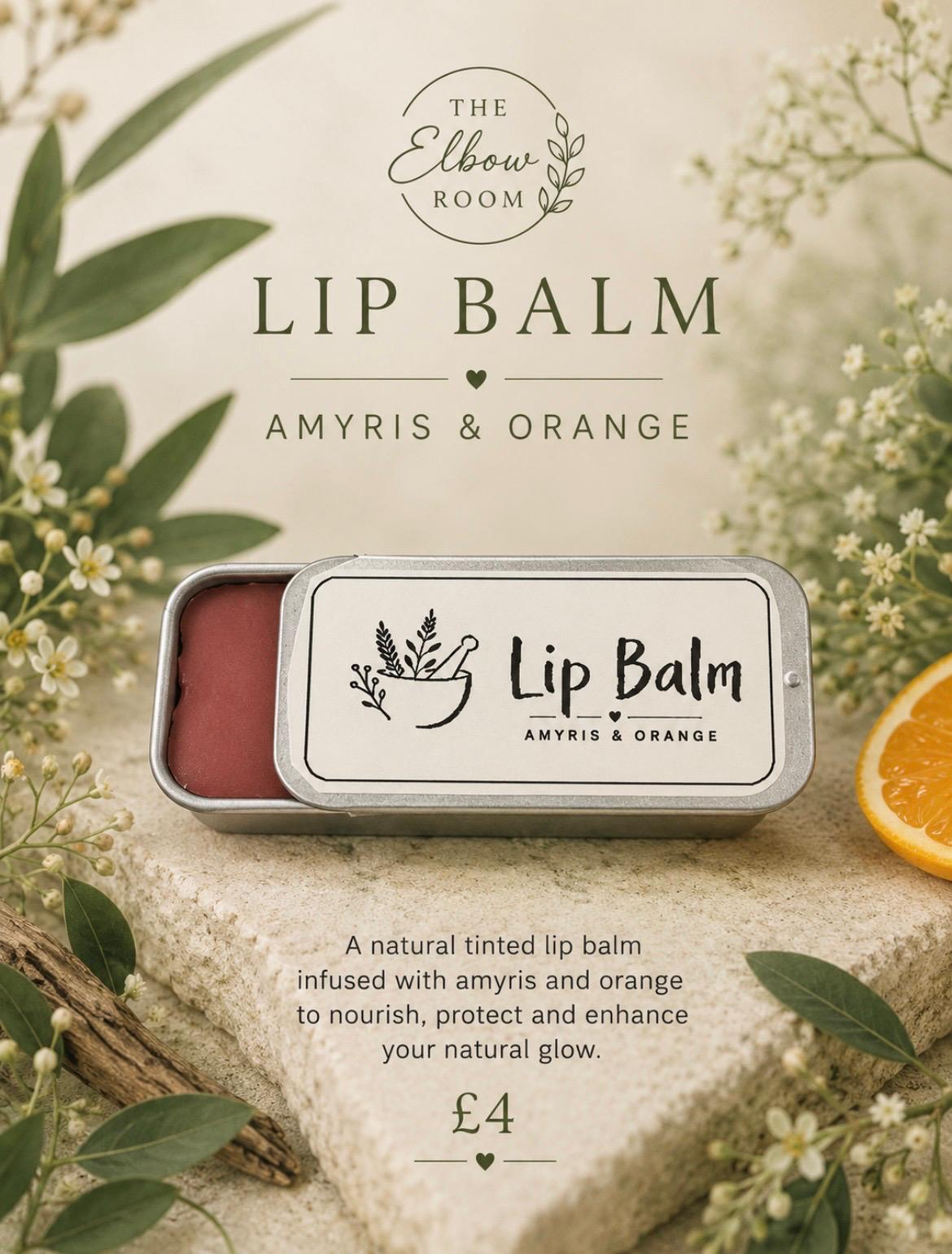 Tinted Lip Balm in Amyris and Orange, sliding tin open beside a slice of fresh orange